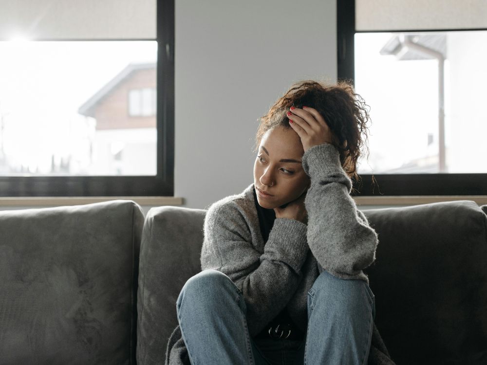 O preço de pensar por conta própria 1 Pessoa pensativa em sofá cinza.