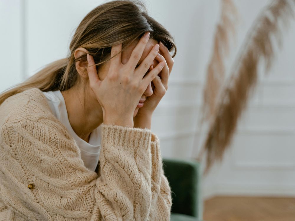 Mulher pensativa com suéter claro.