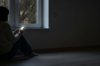 A Psicologia da Solidão Moderna: estamos mais conectados e mais isolados 5 Pessoa sozinha no celular - Solidão Moderna